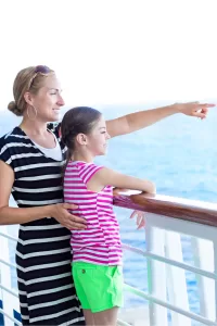 A mother and daughter are on a ship balcony looking out over the water