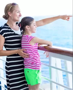 A mother and daughter are on a ship balcony looking out over the water